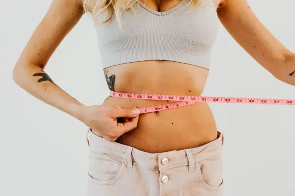 Kobieta mierzy talię centymetrem. Efekty diety 1400 kcal są widoczne.
